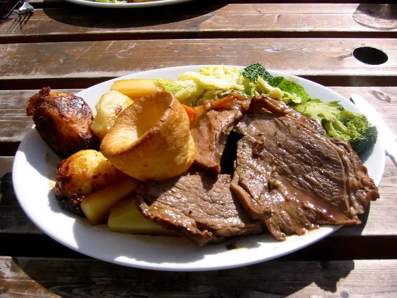 Roast beef dinner with Yorkshire pudding, roast potatoes and greens